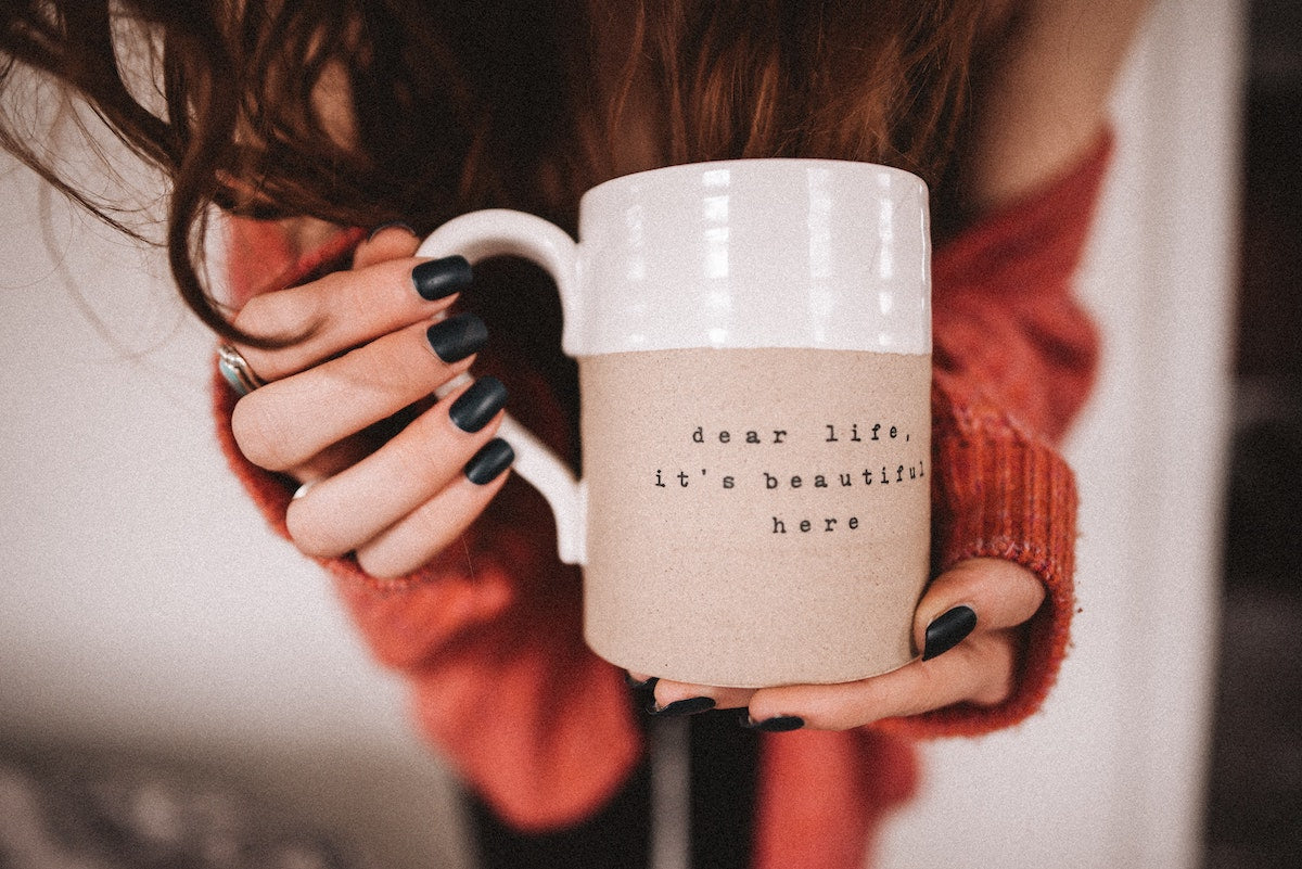 close up of a girl holding mug with inspiring quote on it