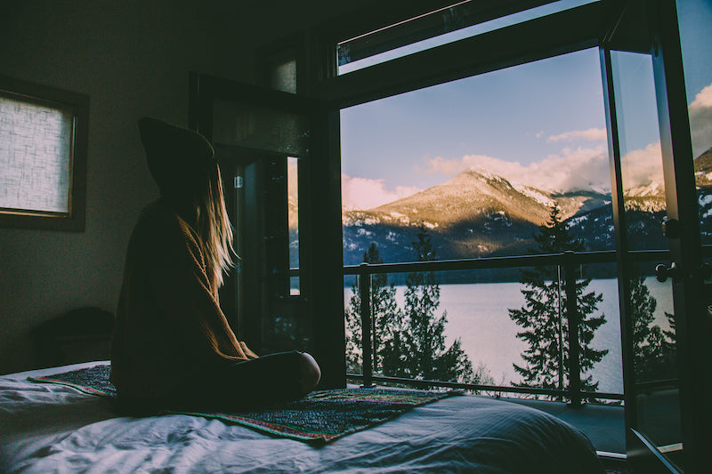 young girl sitting on a retreat center bed looking out into the mountains