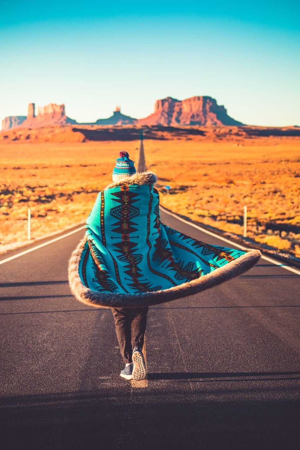 person wrapped in spirithood faux fur throw walking down the road