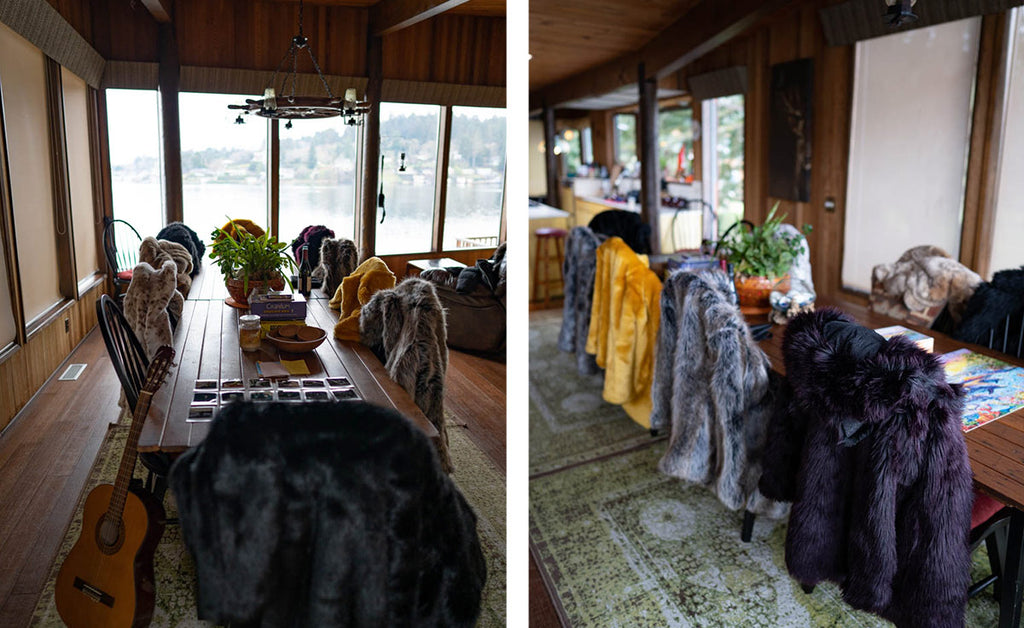 table and chairs in house overlooking lake with different faux fur coats hanging over each chair