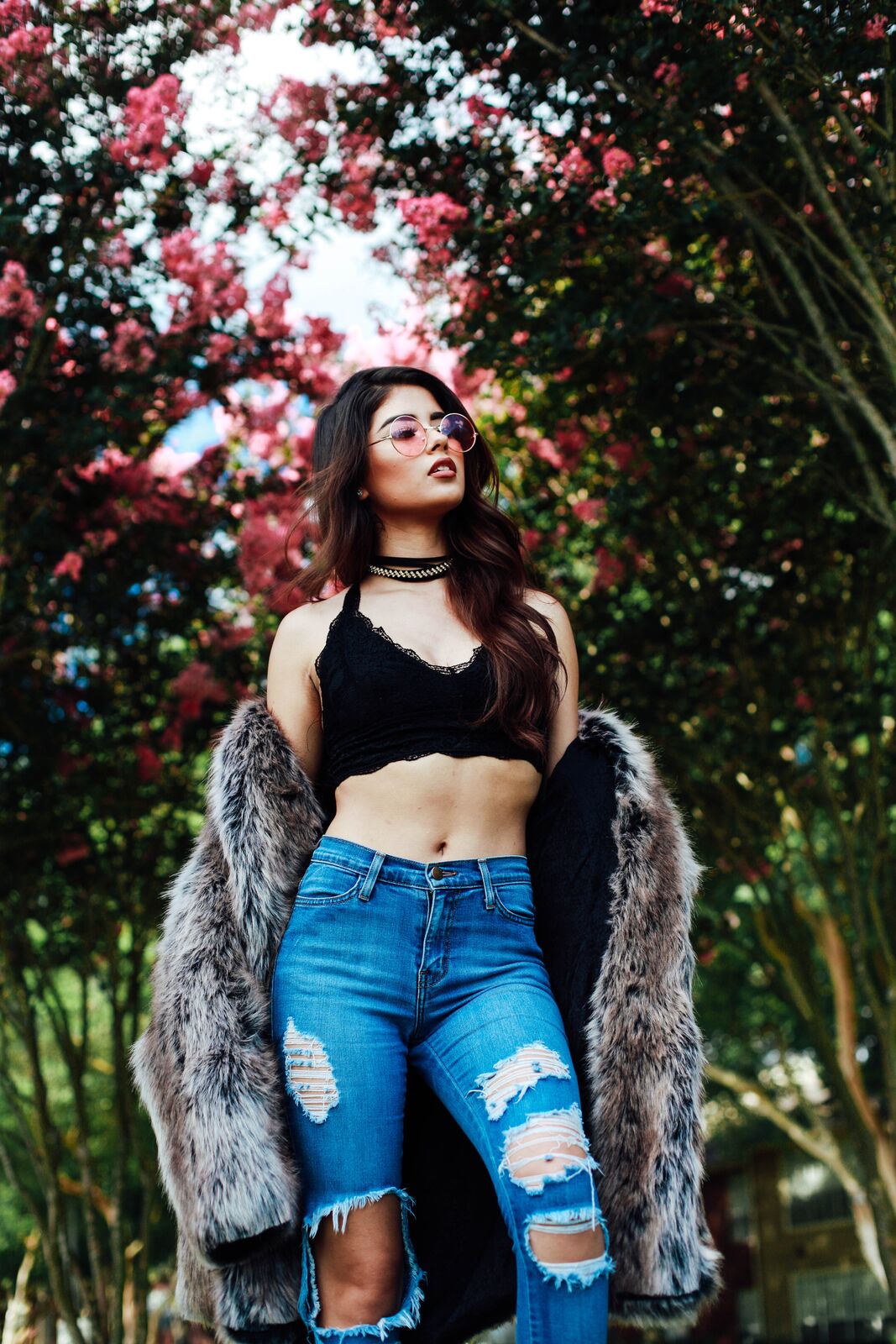 girl wearing ripped jeans, faux fur coat, and sunglasses