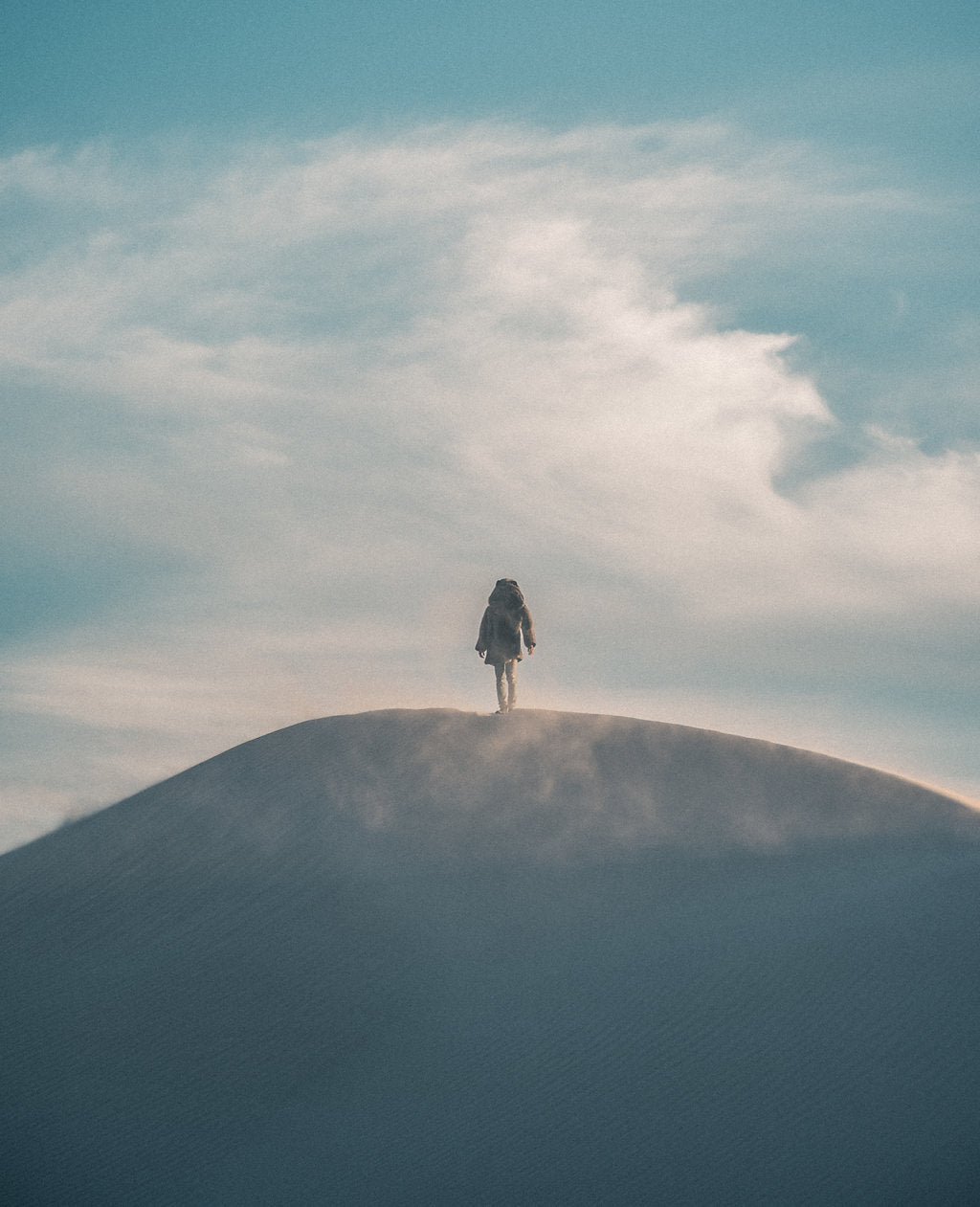 person standing in distance on mountain wearing faux fur coat