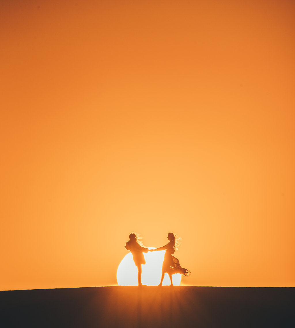 two people facing each other in sun while holding hands