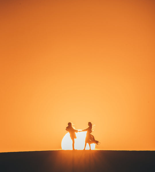 two people in far distance with sun in background