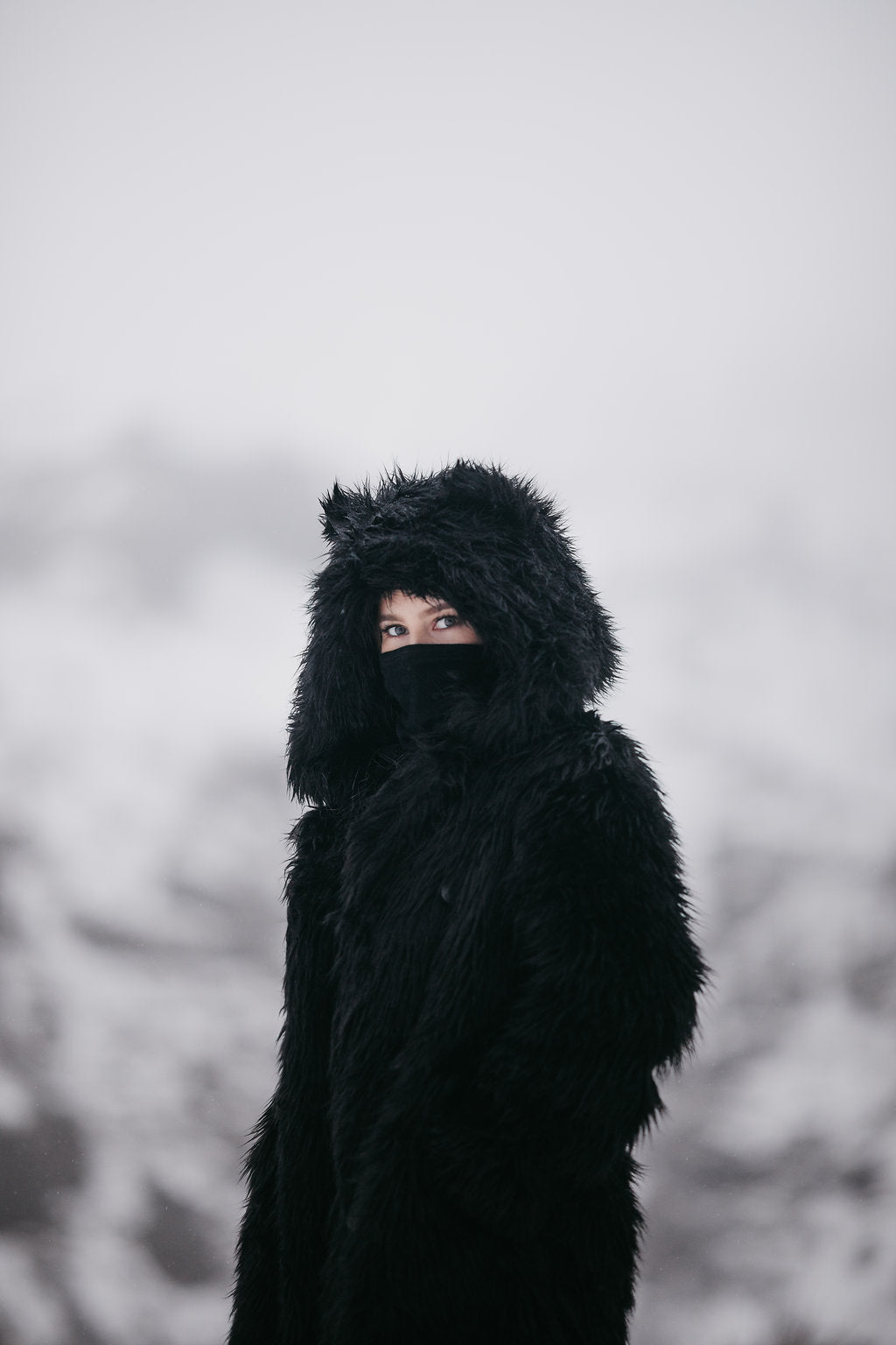 woman wearing black faux fur throw with black mask