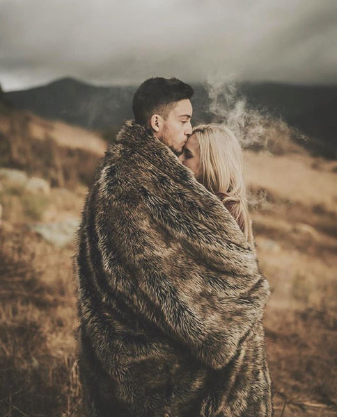 man kissing girls forehead wrapping them both in faux fur throw