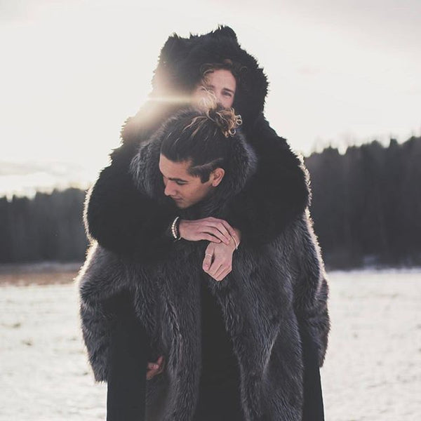 man carrying woman on back while both wearing faux fur coats walking