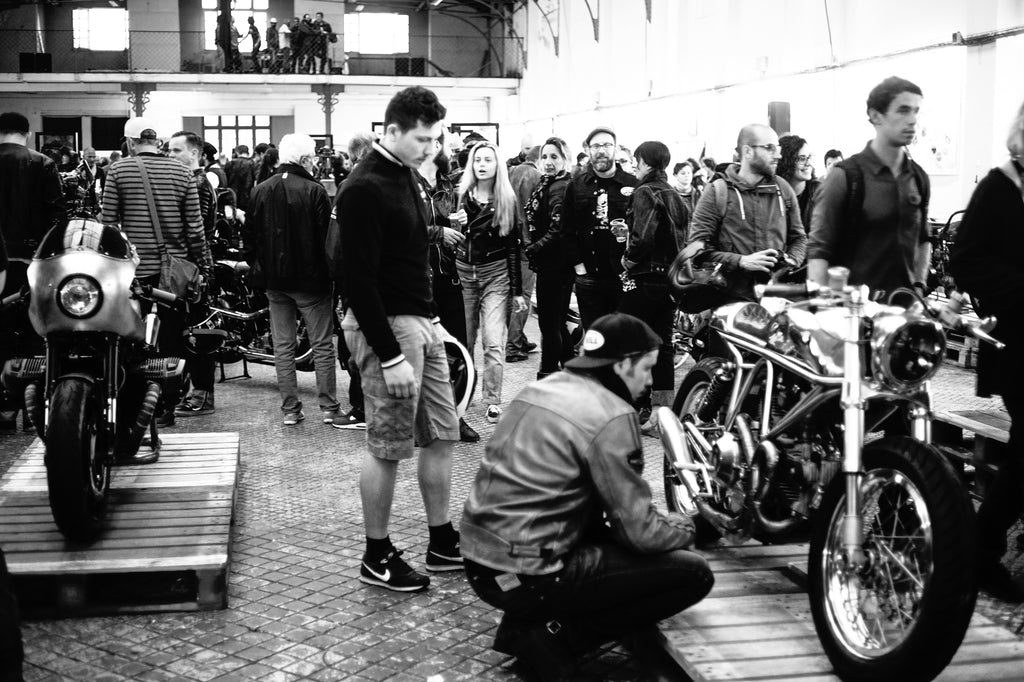 Crowd watching custom motorcycles at Wheels and Waves Festival 2015 dressed in motorcycle jackets and snapbacks, drinking beer