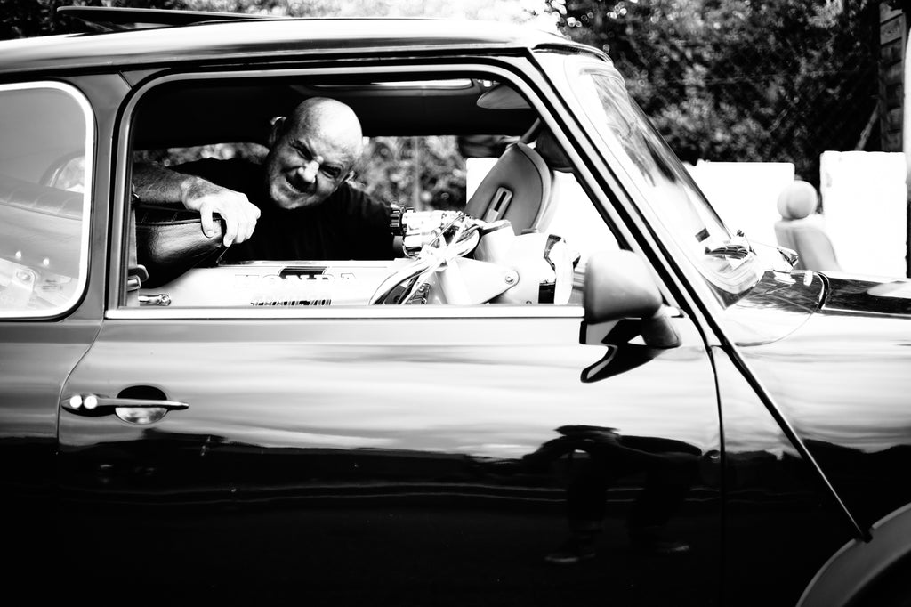 A man pulls a face as he is fitting his moped into his old mini 