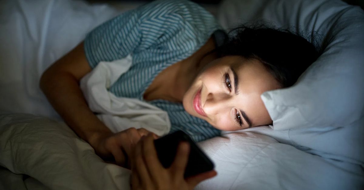 A woman sleeping with her phone, the light emitting in her face.