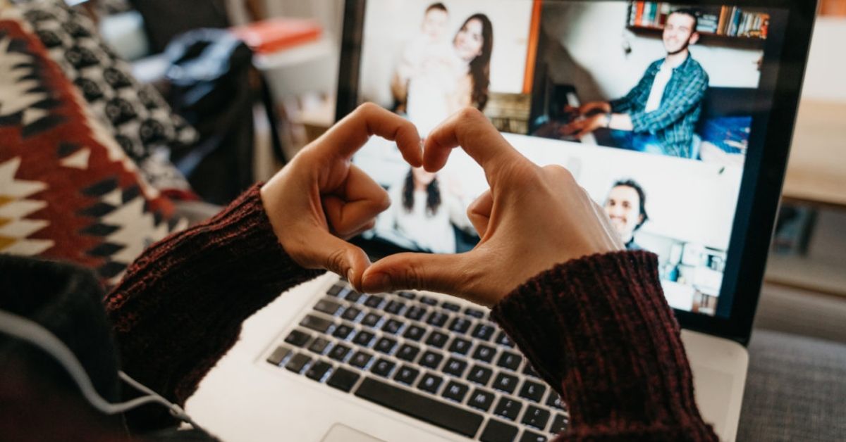 A person using their hands to make a heart shape while sitting in front of a computer camera on a video call.