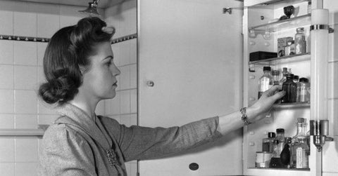 B&W photo of a woman at a medicine cabinet