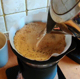 pouring water over ground coffee in a circular motion as slowly as possible from a constant height