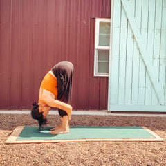 woman using yoga board doing Standing Forward Fold pose