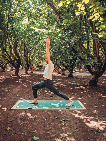 man doing the crescent pose in hazelnut orchard