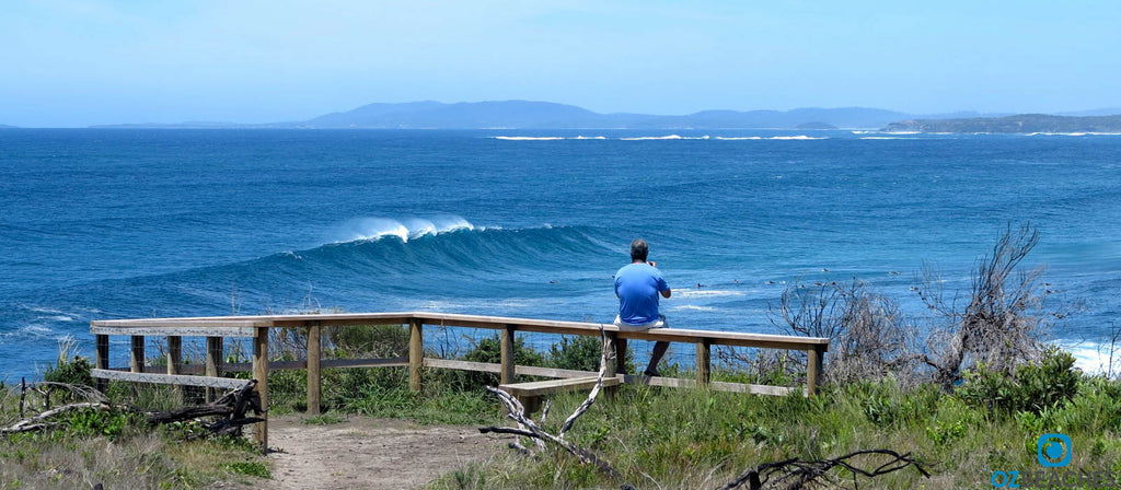 Huge wave rolls into The Bommie at Ulladulla NSW while a photographer watches on