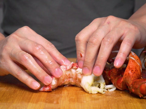 man using hand to de-shell lobster meat 