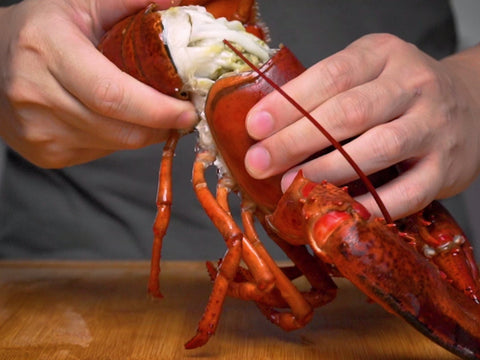 man using hands to crack open boston lobster