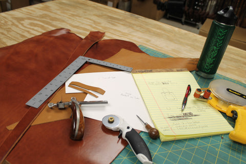 overhead shot of a work table with leather tools and a note pad