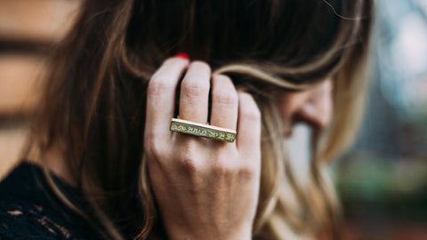 woman brushing hair away wearing Mantra knuckle ring - om mani padme hum 