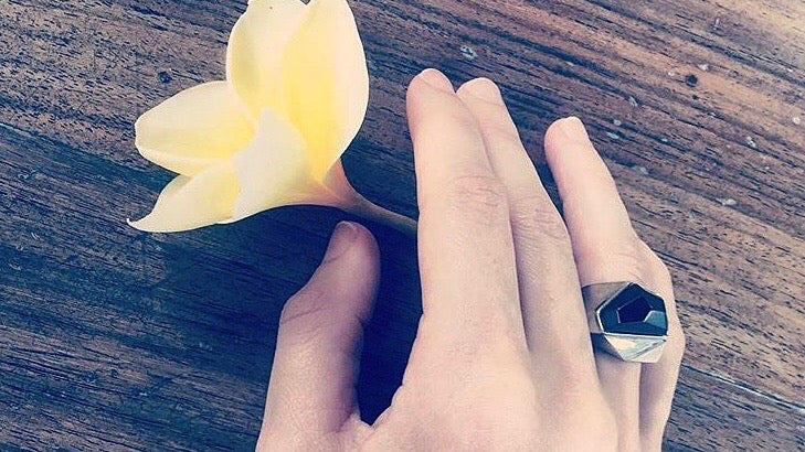 hand holding a yellow flower wearing a Lattice Cocktail Ring with Black Agate.  