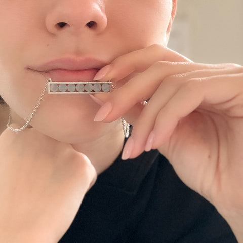 young girl holding Mantra Horizontal Necklace with Round stones to her mouth