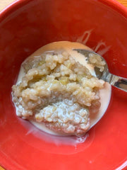 Rhubarb rice porridge with milk served in a red bowl.