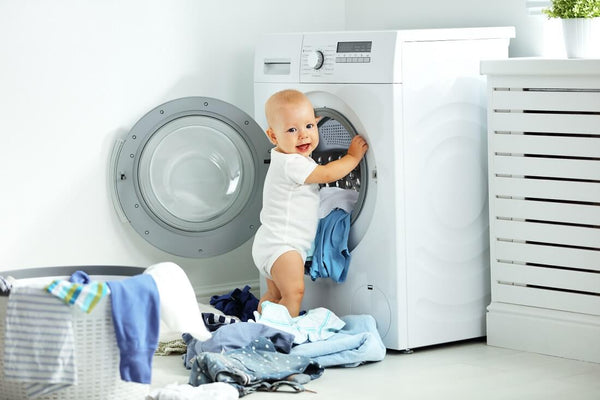 fun happy baby boy to wash clothes and laughs in the laundry room