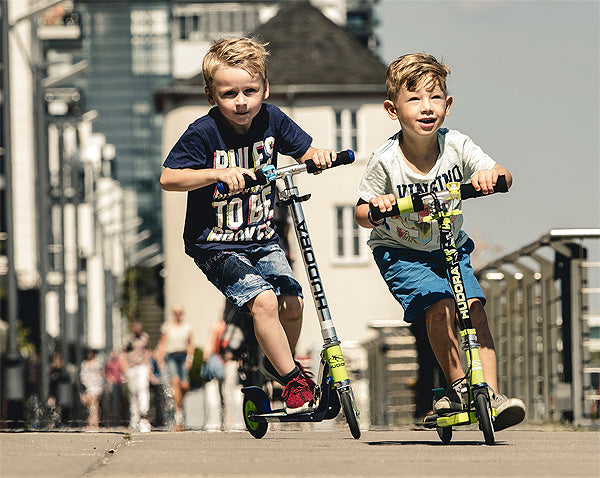 Young boys riding 2 wheel kick scooters