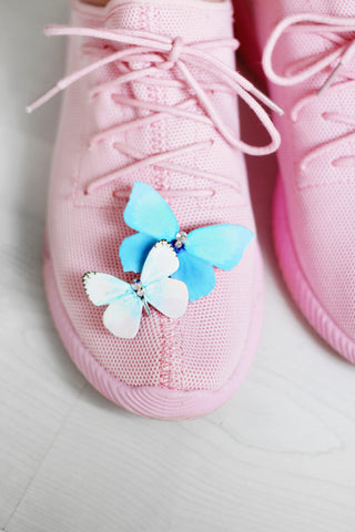 Butterfly brooches pinned to a pair of sneakers.