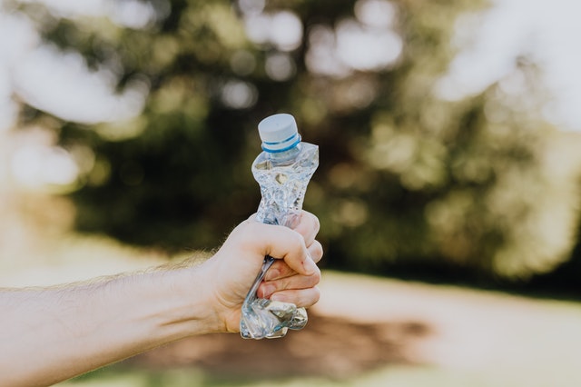 Une main écrasant une bouteille en plastique