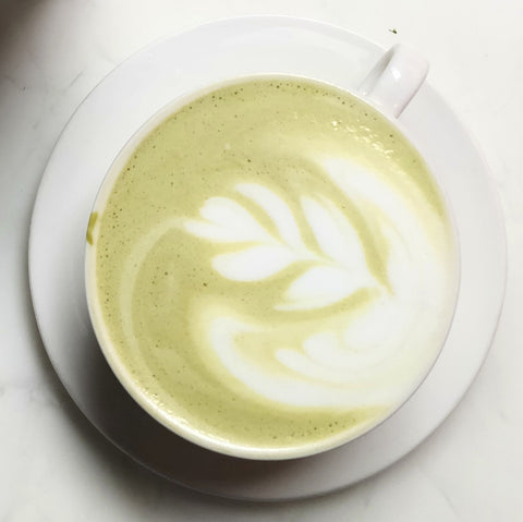 Photo of green tea latte in a white mug on a white background