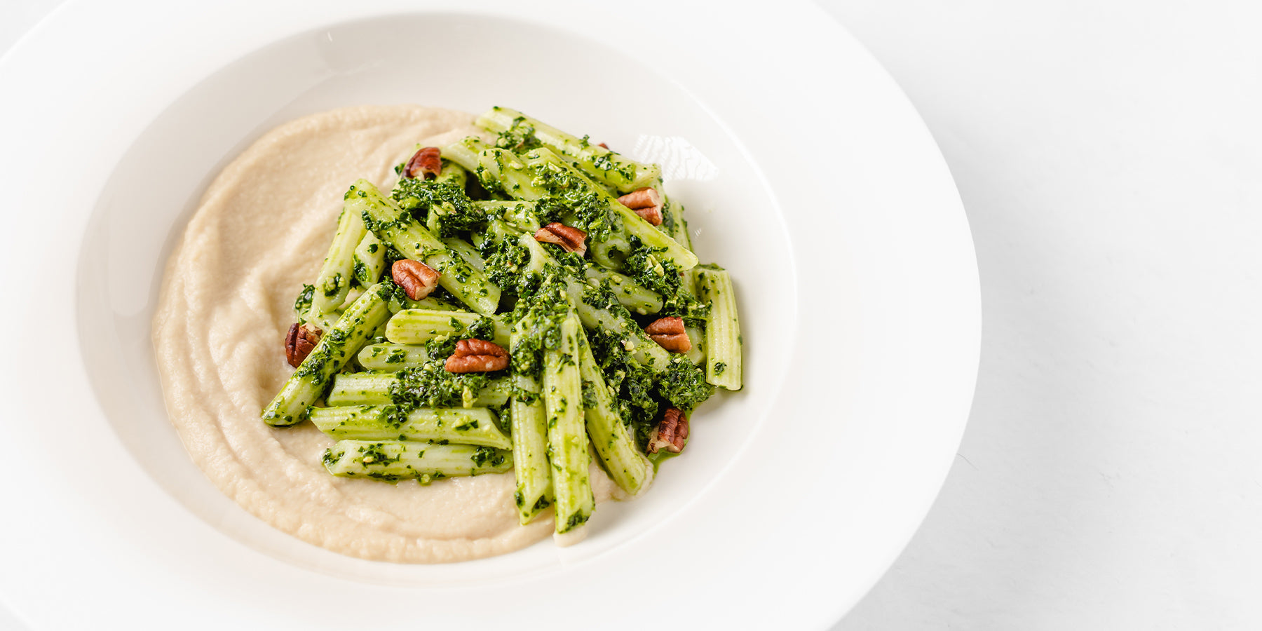 Plate of White Corn Pennette Rigate with Celery Root Cream, Tuscan (Black) Kale Pesto and Rosemary Scented Pecans