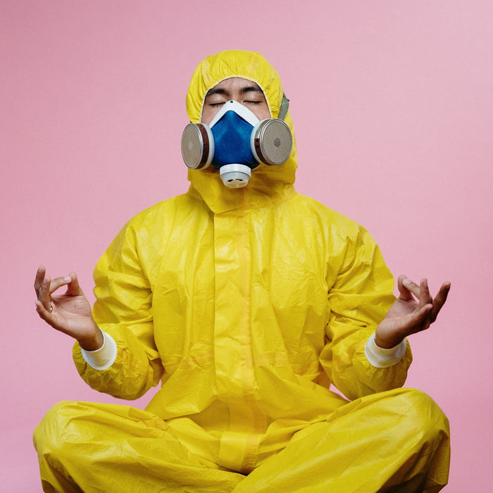 A man wearing a yellow hazmat and blue respiratory mask