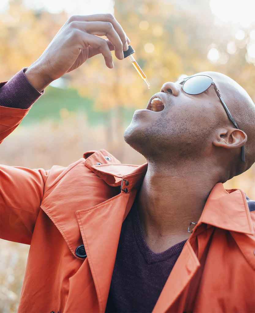 man taking CBD oil through a droplet