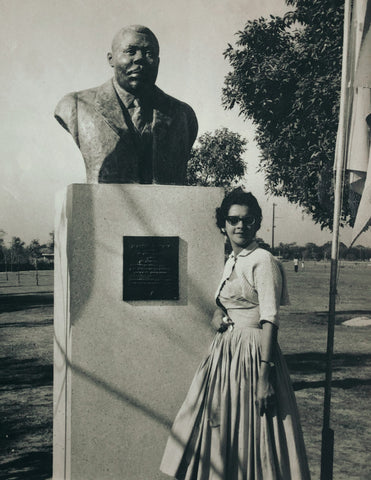 Beautiful woman Standing with huge sculpture of Marcus Garvey Bust by Alvin Marriott