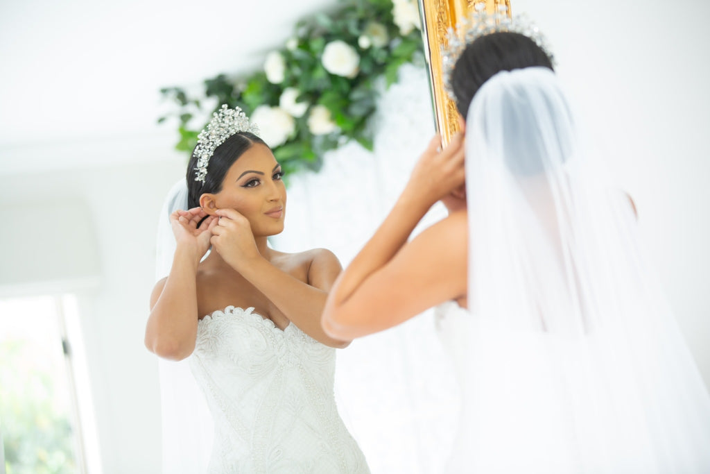 Georgette wearing our Katrina Bridal Crown putting on earrings in the mirror