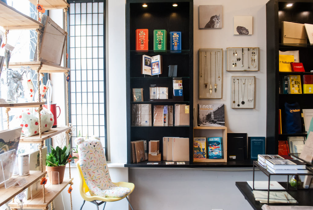 A Craftholic hugging buddy sits and enjoys the store ambiance beside our Midori Traveler's Note display