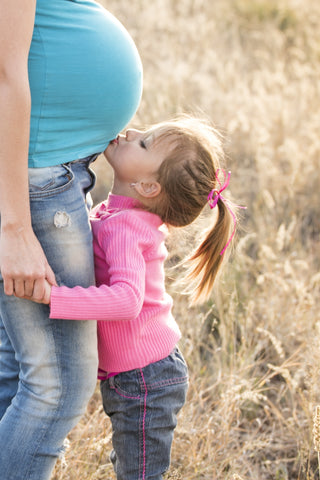 Child kissing pregnant mom belly