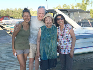 Four people, three Asian and one Caucasian, posing in front of boat.