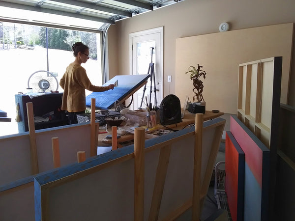 The artist Victoria Primicias painting on a drafting table in her garage studio.