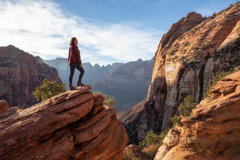 Hiker standing on cliff in front of canyon in Zion National Park