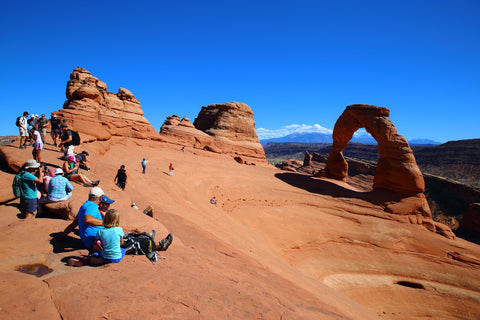 Hikers sitting and looking out over landscape of Delicate Arch in Utah, USA