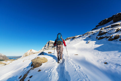 Person hiking across snow covered mountain in Glacier National Park, Montana