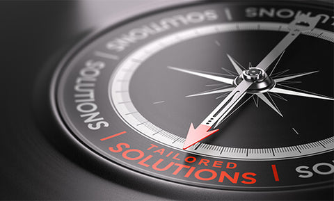Compass pointing to words Tailored Solutions in red.