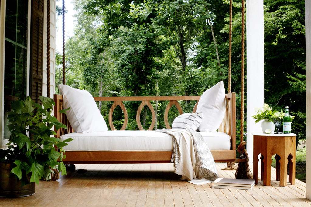 Wooden porch swing with white cushions and oval details