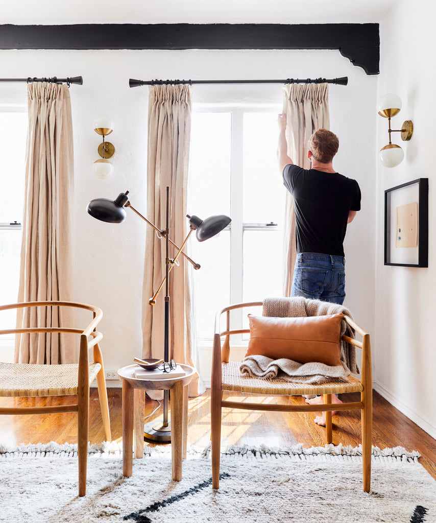 Man styling pleated tan drapes from Barn & Willow