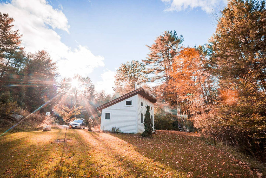 White tiny house in a field of orange Autumn trees