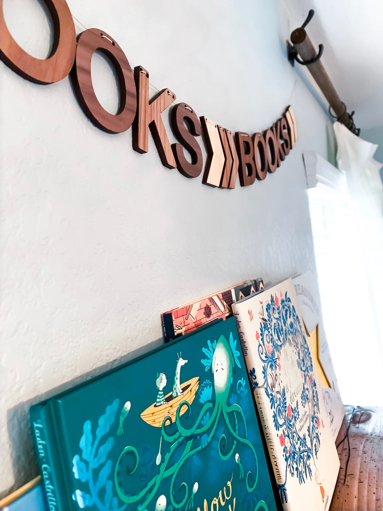 Brooks Gallery Bookshelf wall is now complete with our favorite books, keepsake name puzzle, toys, and a personalized wooden wall bunting to top it off.