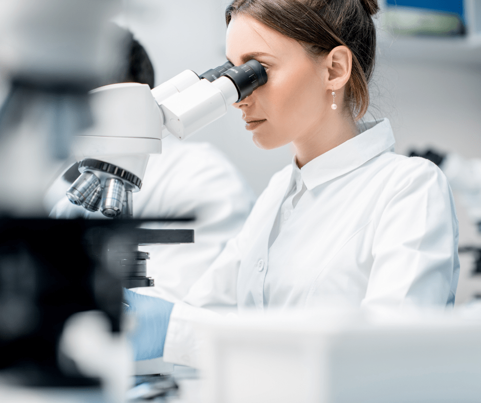 A scientist in the lab looking through a microscope